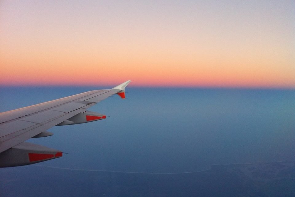 Airplane wing over the sky at sunset